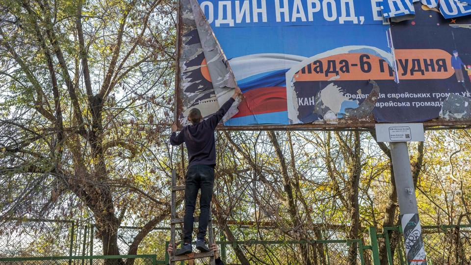 En kæmpe plakat opsat af russiske soldater bliver fjernet, efter at Kherson igen er under ukrainsk kontrol. Flere krigsforbrydelser skal være sket i området, og en FN-gruppe konkluderer, at både russiske og ukrainske krigsfanger har været udsat for tortur. <i>Bulent Kilic/Ritzau Scanpix</i>