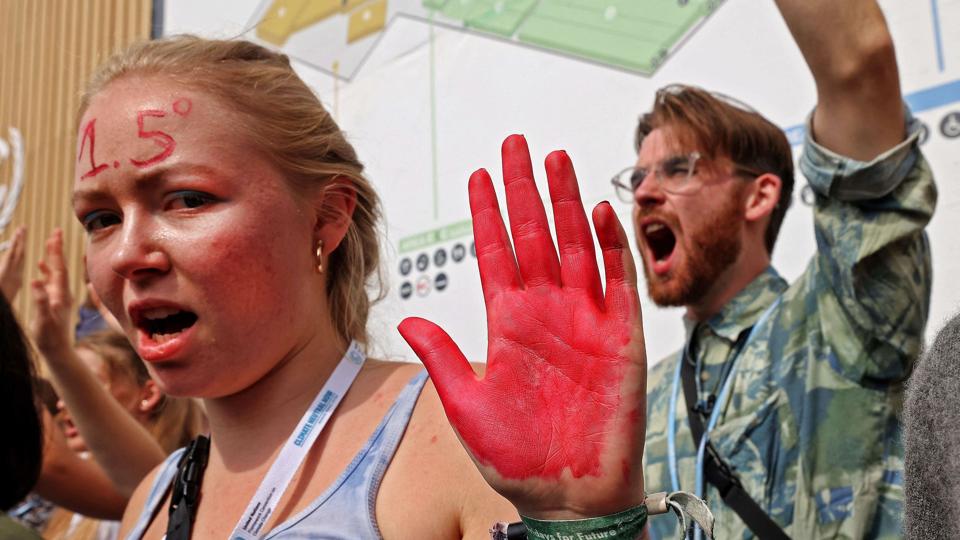 Med rødmalede hænder for at symbolisere blod råber aktivister ved COP27 aktørerne op. De kræver blandt andet klimaretfærdighed for fattige lande. <i>Fayez Nureldine/Ritzau Scanpix</i>