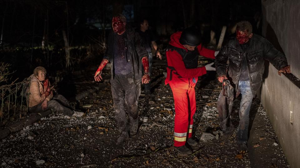 En samarit hjælper natten til fredag lokale beboere, der er blevet såret under de voldsomme russiske bombardementer af den nyligt befriede ukrainske by Kherson. <i>Bernat Armangue/Ritzau Scanpix</i>