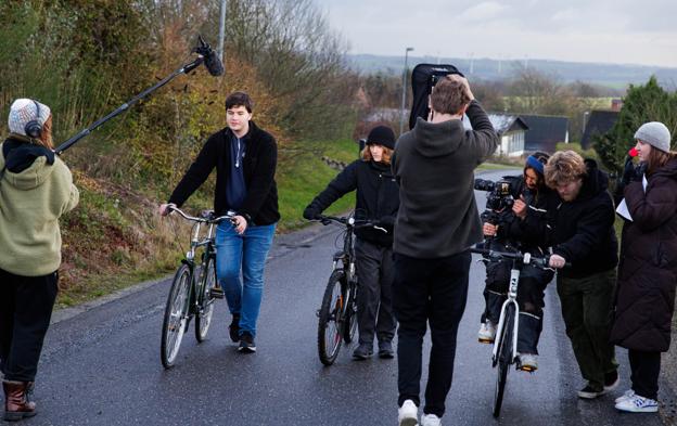 To kammerater på ved op ad Salgjerhøjvej, trækkende på deres cykler, mens fotografen sidder på en tredje cykel. Filmholdet endte dog med at lade fotografen gå, mens hun filmede scenen. 