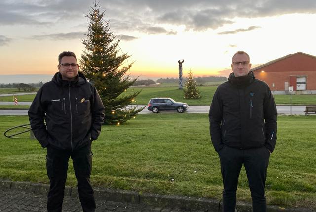 Jonas Jespersen fra Jysk El-teknik (tv.) og direktør Martin Søgaard fra IdealCombi foran de to juletræer, der nu pryder indgangen til Hurup.