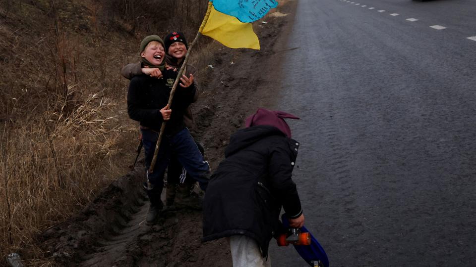 Børn leger i en vejkant udstyret med det ukrainske flag i byen Bakhmut nær frontlinjen i det østlige Ukraine. Byen har været under intense angreb op til den julevåbenhvile, som Rusland ensidigt har bebudet. <i>Clodagh Kilcoyne/Reuters</i>