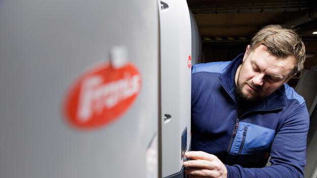Michael Lassen tjekker, hvor meget strøm solcelleanlægget producerer. På en skærm i forretningen kan kunderne også følge med. <i>Foto: Bo Lehm</i>