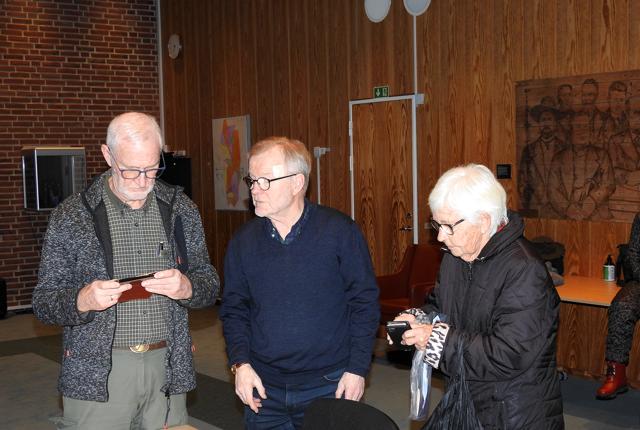 Mogens Mortensen og Kurt Jakobsen er ved at hjælpe Tove Krage med hendes mobiltelefon.