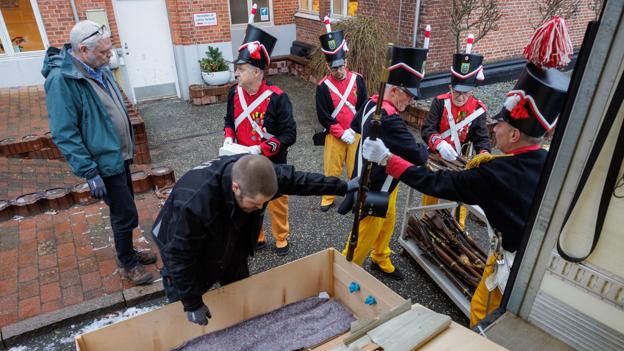 Til venstre museumsinspektør Jørgen Walseth fra Nationalmuseet i samtale med korporal Knud Jørgensen. Museumsassistent Frederik Palm pakker våbenkassen ud, og væbnerne tager imod. <i>Foto: Henrik Bo</i>