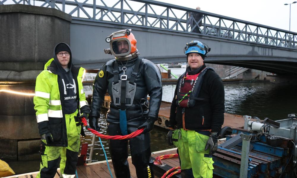 På projektet med Skeppsholmsbron jobbar man som på mest 4 meter djupt vatten. Utöver dykaren finns två extradykare som håller koll från land. På projektet med Skeppsholmsbron jobbar man som på mest 4 meter djupt vatten. Utöver dykaren finns två extradykare som håller koll från land.