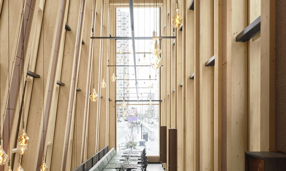 Interiört sätter den svävande träkonstruktionen med höga limträpelare och bjälkar tonen på den nya restaurangen Rummel.