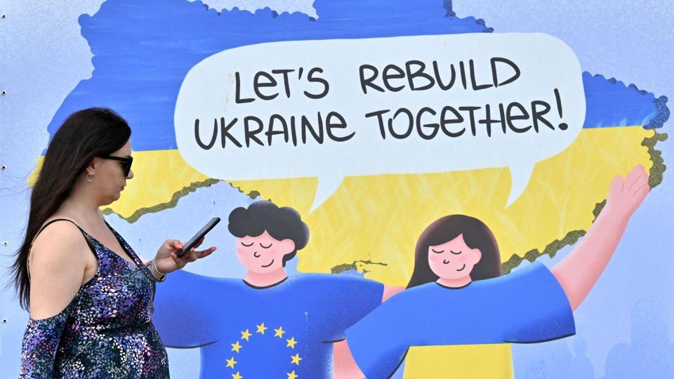Foråret er kommet til Kyiv, hvor en kvinde onsdag gik forbi en plakat med teksten "lad os genopbygge Ukraine sammen". <i>Sergei Supinsky/Ritzau Scanpix</i>