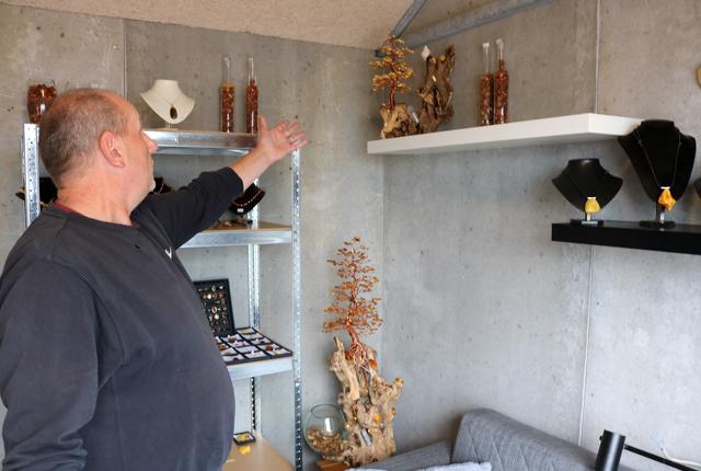 Carsten Kragelund viser et par af sine dekorative ravtræer, som han sælger fra sin lille butik.