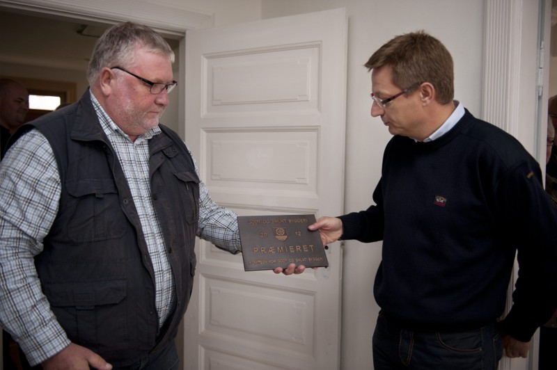Sådan så det ud for 10 år siden, da advokat Mogens Kjær (th.) modtog prisen for godt og smukt byggeri af Ib Johansen fra priskomiteen. Den omfattende restaureringen vakte begejstring i Komitéen for Godt og Smukt Byggeri i Løgstør, som præmierede huset. Efter komitéen troppede op og overrakte bronzepladen har den siden været monteret på huset som et kvalitetsstempel.