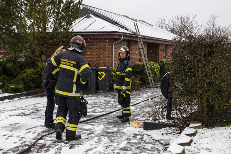 Brandfolk fra Nordjyllands Beredskab i Aalborg fik værdifuld assistance af en pensioneret kollega som via stigen i baggrunden kom så højt op, at han kunne sprøjte vand ned til den kraftige brand på loftet. Foto: Martél Andersen