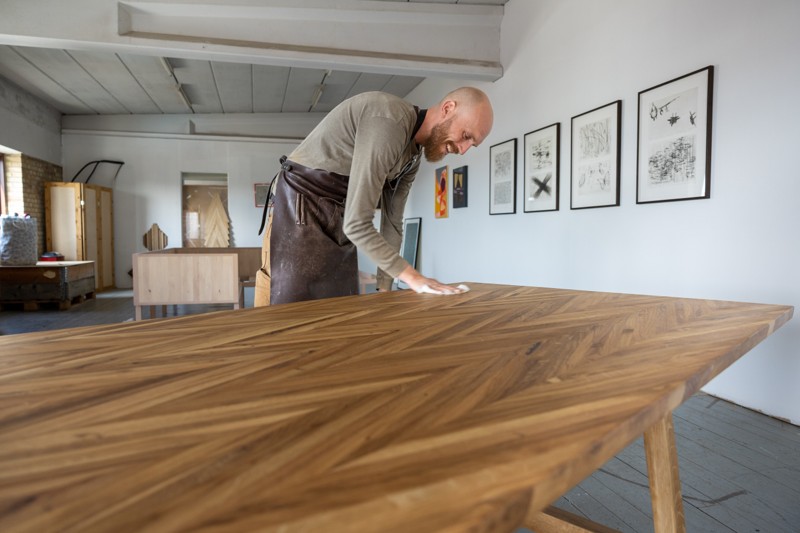 Håndværket og kærligheden til træ driver Klaus Grønning. Her med et spisebord lavet af gulvet fra en sportshal.
