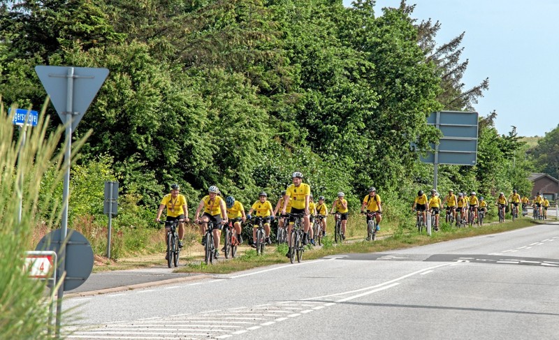 De cirka 30 gulklædte unge cykelryttere ankommer her til rundkørslen ved MTH Biler i Løgstør. Foto: Mogens Lynge