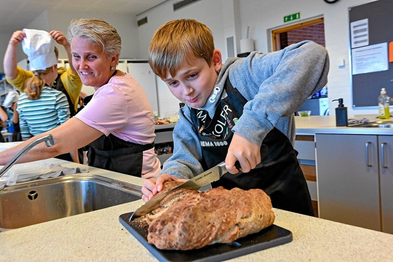 Uhhmmm - børnenes langtidshævede brød med sprød-sprød skorpe smagte forrygende. Her er det Joachim på 11 år, der bruger alle kræfter på at lave skiver til kammeraternes suppe. Foto: Ole Iversen