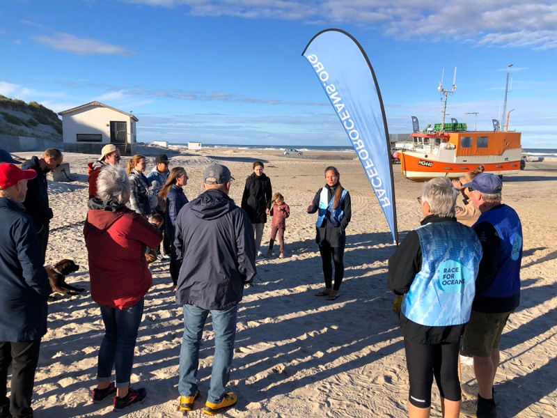 Signe Simonsen (i midten) er initiativtager til Race for Oceans. Her byder hun velkommen til en tidligere affaldsindsamling på stranden i Løkken.