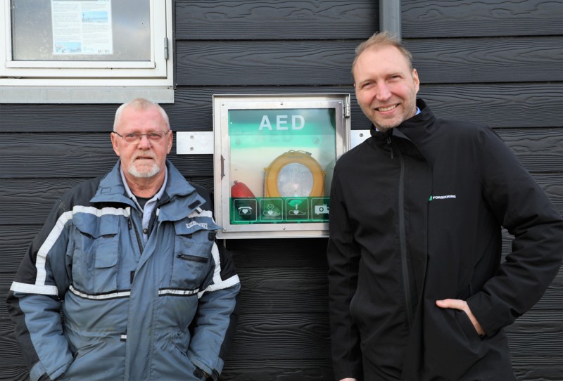 På en blæsende torsdag i november kiggede Lasse Rytter Leander (th) forbi på havnen og overrakte hjertestarteren til Bent-Ole Jensen. Den er nu klar til at redde liv, opsat på siden af Sillerslev Huset.
