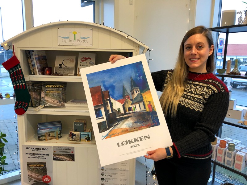 Bureauchef Amalie Andersen viser årets Løkkenplakat. Plakaten kan, i lighed med andre lokale publikationer, købes på Løkken Turistbureau.