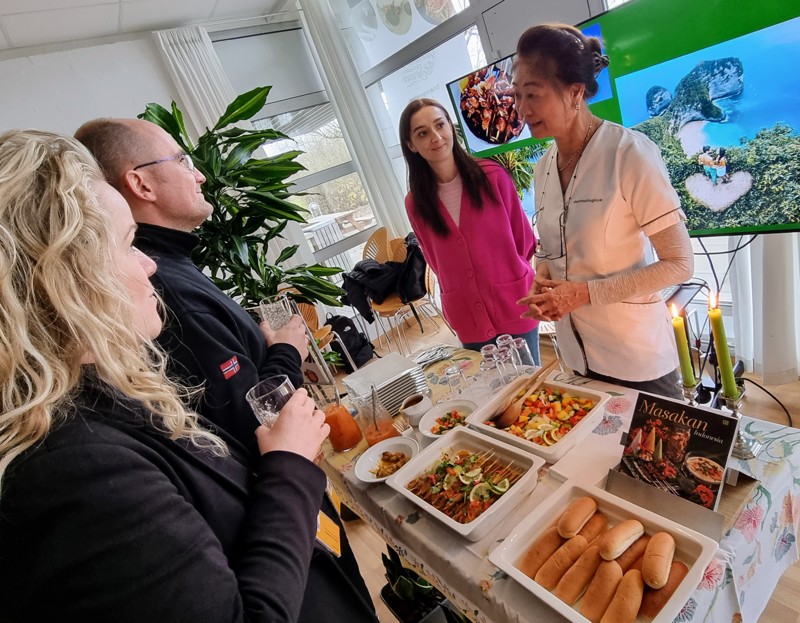 Fra venstre Merry Julianti fra grundforløb 2 på kokkeuddannelsen og Inna Demianenko fra EUD Business-uddannelsen serverer Satay-kylling med grøntsager for nogle ansatte fra EUC Nord.