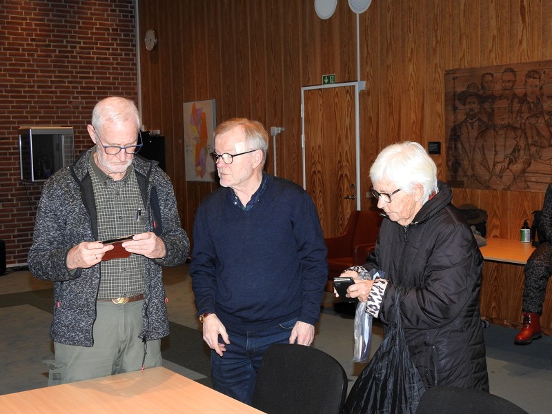 Mogens Mortensen og Kurt Jakobsen er ved at hjælpe Tove Krage med hendes mobiltelefon.