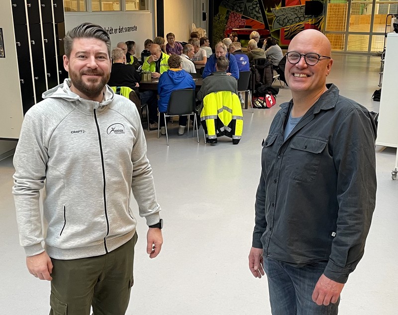 Claus Jacobsen (th) med sin afløser som centerchef; Morten Hald (tv). Bagved ses 30-40 seniorer, der drikker kaffe og hygger efter at have været aktive. Noget af det, som Arden Hallerne kan.