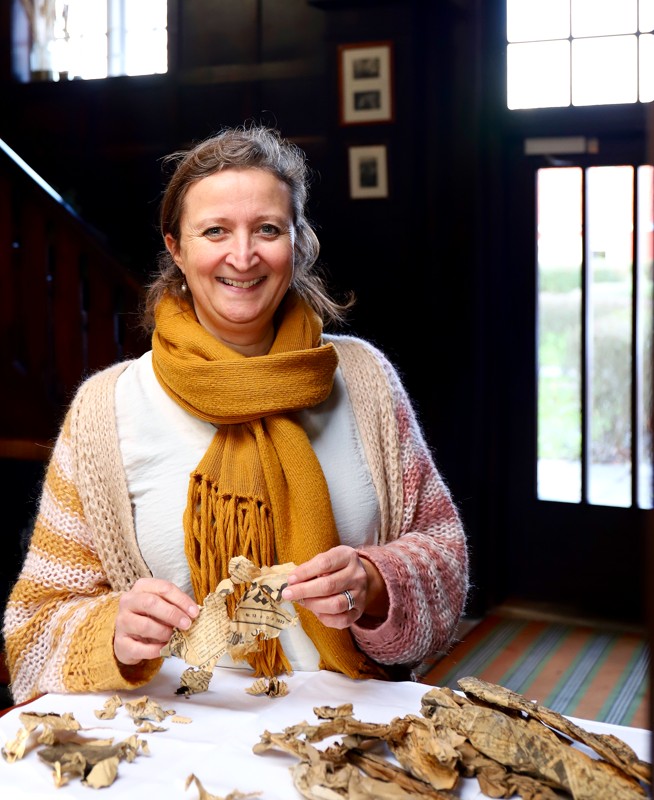 Receptionist Caroline Røntved med den gamle avis fra 1933 med billeder af Stauning fundet imellem vinduesrammerne da de blev skiftet ud.