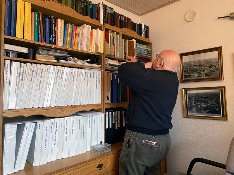 Masser af ringbind med Hjallerups historie står side om side i reolen hos Carl Jensen.