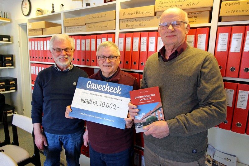 Lokalhistorisk Arkivs formand, Geert Lissau, og arkivleder Erik Præsius får her overrakt en gavecheck af Frits Danielsen, formand for Støtteforeningen for Dronninglund Sygehus.
