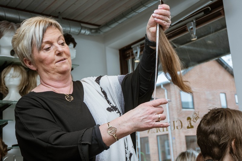 Lene Møller Hansen fra Hårguiden måler det afklippede hår og konstaterer, at længden er ok. Hår, der doneres væk til fremstilling af parykker, skal minimum være 23-25 cm langt.