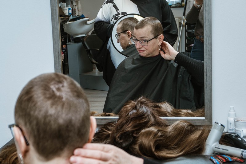 Efter klipningen er håret trimmet helt kort, og Kjersti Hagen studerer resultatet i spejlet.