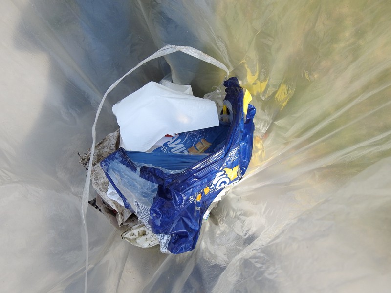 et kig ned i hans pose viser store mængder plast affald.